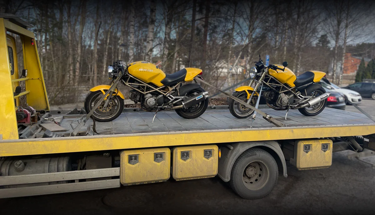 Två gula motorcyklar på flakbil — skrotamc.se